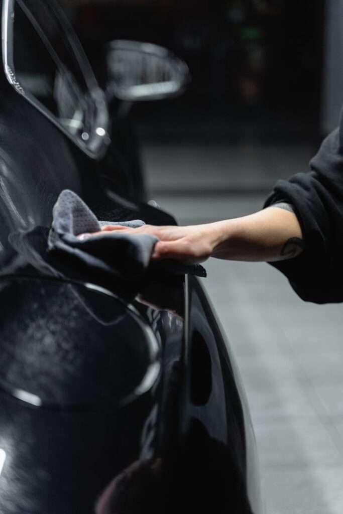 A Person Wiping a Car with a Cleaning Cloth